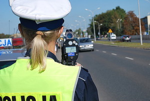 policjantka stojąca na drodze z miernikiem prędkości