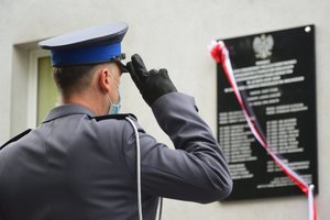 Policjant oddający honory pod tablicą pamiątkową