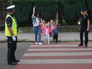 policjanci nadzorują przechodzenie przez przejście grupki dzieci wraz z opiekunem