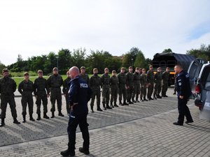 na fotografii żołnierze WOT stojący w szeregu przygotowują się do wykonania komendy do ćwiczenia, przed nimi prowadzący szkolenie dwaj policjanci prewencji