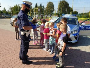 policjanci z dziećmi na tle radiowozu