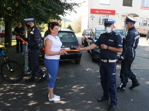 policjant ruchu drogowego wręcza odblask kobiecie na chodniku
