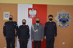 Fotografia przedstawia Komendanta Miejskiego Policji w Przemyślu podinsp. Piotra Mazura oraz trzech nowo przyjętych policjantów. W tle widoczne jest godło Polski oraz logo KMP Przemyśl