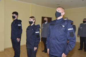 Fotografia kolorowa - na pierwszym planie widać trzech nowo przyjętych policjantów składających rotę ślubowania. W tle zdjęcia widać kadrę kierowniczą KMP w Przemyślu.