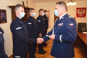 Policjant odbiera legitymację służbową z rąk Komendanta Wojewódzkiego Policji w Rzeszowie nadinspektora Henryka Moskwy. Wszyscy uczestnicy uroczystości w maseczkach