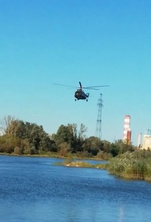 Na zdjęciu policyjny śmigłowiec nad rzeką Wisłą biorący udział w poszukiwaniach zaginionej kobiety, w tle widać elektrownię w Połańcu.