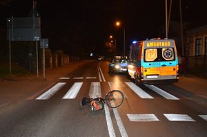 Przejście dla pieszych, pora nocna. Na jezdni przed przejściem lezy rower. W tle ambulans i radiowóz.