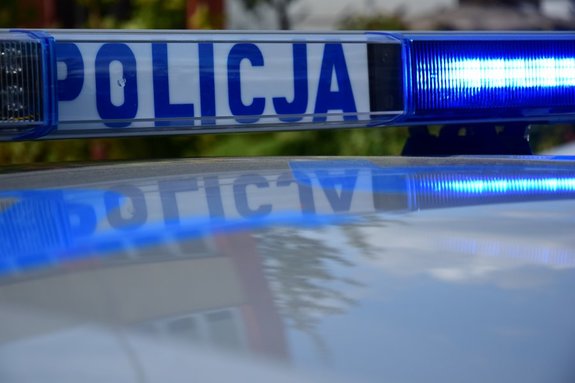 Policyjna belka z włączonym niebieskim światłem i napisem POLICJA