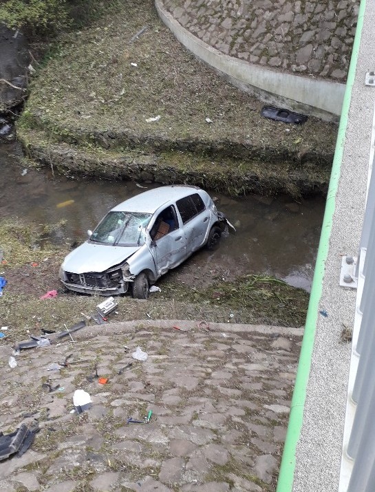 Na zdjęciu uszkodzony pojazd marki Renault, który częściowo znajduje się w rzece.