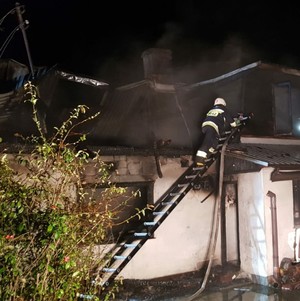 Na zdjęciu strażak na drabinie podczas gaszenia poddasza budynku.