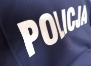 Zdjęcie przedstawia tylna część bluzy policyjnej koloru granatowego z białym napisem POLICJA na środku