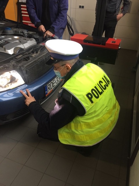 Policjant kontrolujący reflektory samochodowe.