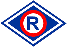 Zdjęcie kolorowe przedstawia naszywkę wydziału ruchu drogowego w kształcie rombu koloru niebiesko czerwonego, w środku umieszczona litera R w kolorze srebrnym