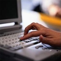 Na zdjęciu widać komputer i ręka, która dotyka klawiaturę