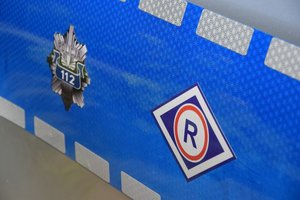Drzwi policyjnego radiowozu, na nich symbol ruchu drogowego oraz policyjna gwiazda z napisem Policja i 112