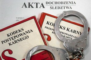 Zdjęcie kolorowe przedstawia – teczkę akt dochodzeniowo- śledczych, na której leży dwie książki o tytule kodeks karny oraz Kodeks Postępowania Karnego. Na kodeksach są położone kajdanki w kolorze srebrnym.