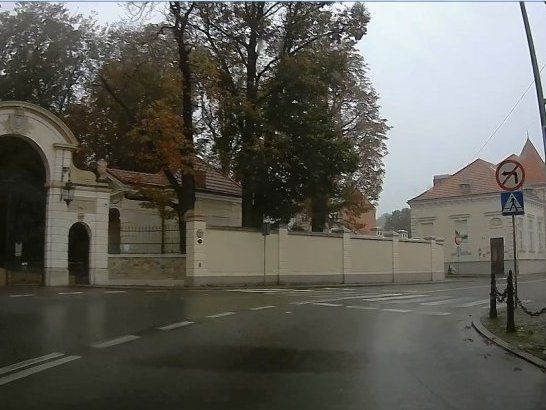 Zdjęcie przedstawiające ulicę Kościuszki w Łańcucie. Po lewej widoczna brama główna łańcuckiego parku. Po prawej znak przejście dla pieszych. Na środku jezdnia z wymalowanymi białymi pasami.