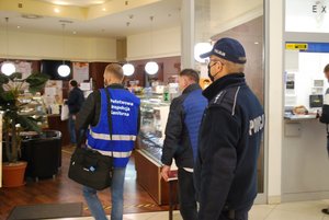 Wspólne działania policji i inspekcji sanitarnej. Na zdjęciu policjant i pracownik sanepidu kontrolujący sklep w galerii handlowej pod kątem przestrzegania obowiązujących przepisów.