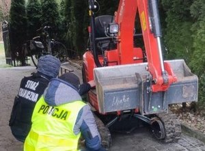 dwaj mężczyźni przy koparce, na kamizelkach mają napis policja i straż graniczna