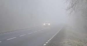 Zdjęcie przedstawia jadący pojazd po drodze podczas gęstej mgły