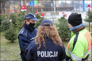 Kontrole punktów sprzedaży choinek w Tarnobrzegu. Na zdjęciu dwie umundurowane policjantki sprawdzają dokumenty sprzedającego mężczyzny. Zdjęcie wykonano w      dniu 23 grudnia 2020r.