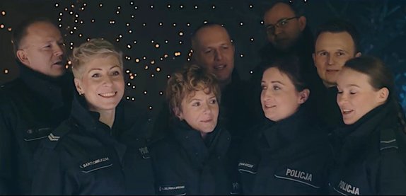 Grupa umundurowanych policjantów śpiewa kolędę