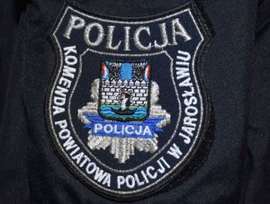 Haft z napisem o treści Policja, Komenda Powiatowa Policji w Jarosławiu oraz odznaka policyjna  z herbem jarosławia