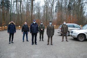 Zdjęcie grupowe na terenie miejsca postojowego. Na na pierwszym planie Komendant Komisariatu podinspektor Waldemar Jędrzejewski i Nadleśniczy Piotr Brewczyński. Na drugim planie cztery osoby reprezentujące wykonawcę robót i nadleśnictwo.