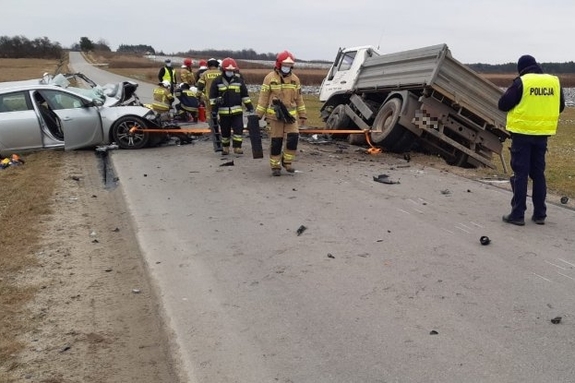 Na zdjęciu policjanci i strażacy na miejscy wypadku w Stobiernej. Obok drogi, na poboczu stoją uczestniczące z zdarzeniu samochody, ciężarowy Man i rozbity opel instgnia,