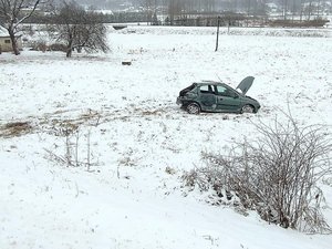 Rozbity samochód peugeot stoi na zaśnieżonej łące. Tyl samochodu jest uszkodzony