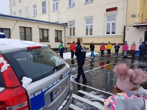 policjantka podczas spotkania przed budynkiem szkoły SP nr 1 w Mielcu wraz z dziećmi i nauczycielkami, na fotografii widnieje również radiowóz