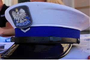 Zdjęcie –Przedstawia czapkę policyjna funkcjonariusza ruchu drogowego w randze sierżanta. Czapka galowa koloru białego z niebieskim otokiem i czarnym daszkiem, na środku otoku naszyta jest tz (Fałka) oznaczająca stopień policjanta .