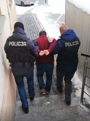 Dwóch policjantów doprowadza zatrzymanego