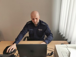 policjant siedzący przed komputerem w czasie trwania lekcji online