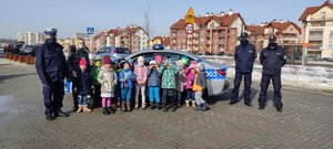 Zdjęcie pamiątkowe policjantów i dzieci na tle radiowozu