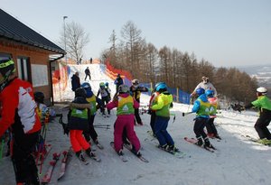 1.Zdjęcie kolorowe przedstawia stok narciarski w Przemyślu-na zdjęciu widoczne dzieci oraz trener który pokazuje dzieciom pozycję do zjazdu na nartach