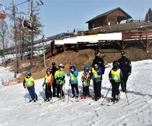 2   Zdjęcie kolorowe przedstawia stok narciarski w Przemyślu –w tle stoją dzieci na nartach oraz policjanci