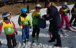 Zdjęcie kolorowe przedstawia stok narciarski w Przemyślu- na zdjęciu widoczne dzieci oraz z prawej strony policjantka rozdająca prezenty