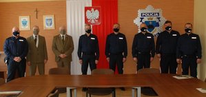 .-Zdjęcie przedstawia aulę w Komendzie Miejskiej Policji w Przemyślu .W tle widoczna jest ściana na środku której umieszczona jest flaga Polski z orłem wykonanym z metalu. Po prawej stronie zawieszone  jest logo policji tj. gwiazda policyjna   . Z lewej strony flagi zamieszczone są dwa herby –miasta Przemyśl oraz powiat przemyskiego . Na Przednim planie zdjęcia zaczynając od strony prawej stoją trzej policjanci z Komisariatu Policji  w Dubiecku koło nich stoi I zastępca KMP w Przemyślu podkom.Waldemar Kolczak następnie Z-ca KMP w Przemyślu podinsp. Rafał Dyś. Koło komendanta Stoi Nadleśniczy Przemysław Włodek oraz Komendant Straży Leśnej Krzysztof Porczak. Z Lewej strony widoczny Komendant Komisariatu w Dubiecku kom. Witold Bednarczyk.