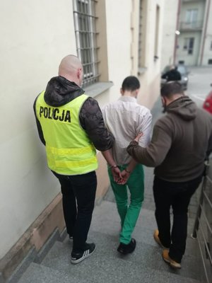 Dwóch policjantów wyprowadzających z budynku zatrzymanego mężczyznę