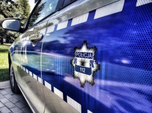 Bok policyjnego radiowozu, na którym widnieje napis Policja i numer alarmowy 112 umieszczony  w policyjnej gwieździe