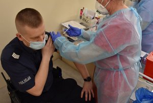 Pielęgniarka podaje  szczepionkę umundurowanemu policjantowi