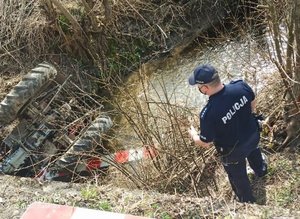 Miejsce tragicznego wypadku, do jakiego doszło w Ulanicy w powiecie rzeszowskim. Na zdjęciu widać rzekę, do której wpadł ciągnik rolniczy biorący udział w wypadku oraz funkcjonariusza.