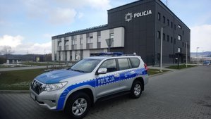 nowy terenowy radiowóz Toyota Land Cruiser na tle budynku Komendy Powiatowej Policji w Lesku