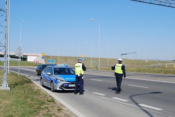 Na zdjeciu policjanci drogówki zatrzymujący na drodze samochód do kontroli.