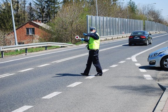 Policjant ruchu drogowego wydający tarczą sygnał do zatrzymania pojazdu