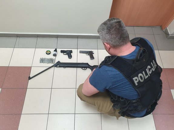 policjant wydziału kryminalnego prezentuje broń zabezpieczoną przez funkcjonariuszy