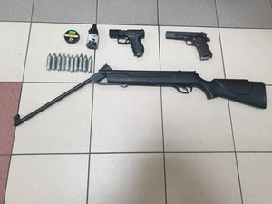 broń zabezpieczona przez policjantów podczas przeszukań w mieszkaniach zatrzymanych mężczyzn, na fotografii dwie jednostki broni krótkiej oraz strzelba, a także śruty i naboje gazowe
