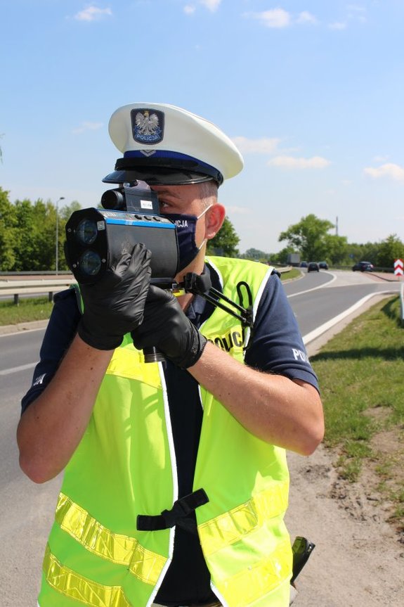 Policjant ruchu drogowego prowadzi kontrolę pomiaru prędkości.