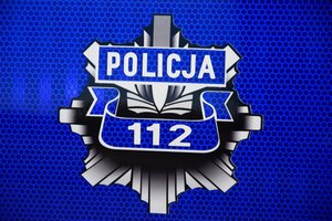 Policyjna odznaka z nr alarmowym 112 i napisem Policja